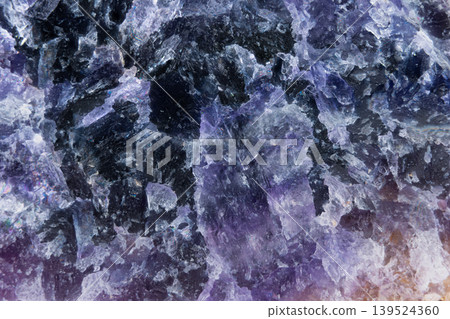 Close examination highlights dark mineral pockets and vivid textures. Detailed shot showcasing coarse crystalline grains and intense color contrasts in amethyst matrix 139524360