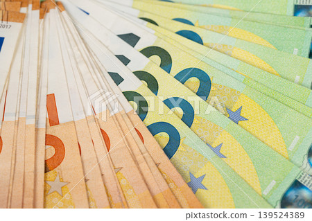 Vivid closeup of euro banknotes creating decorative background. Dynamic pattern formed by fanned euro banknotes with shimmering and colorful effects for visual design 139524389