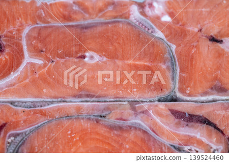 Frozen salmon slices display in freezer with condensation and neat briquette rows, cool lighting, consumerready feel, vivid orange flesh and skin borders visible Frozen salmon slices display in freezer with condensation and neat briquette rows, cool lighting, consumerready feel, vivid orange flesh and skin borders visible 139524460