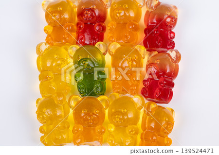 Stacked marmalade gummy bears with green standout accent, repeating warm tones interrupted by single contrasting piece, playful composition evokes novelty and focus Stacked marmalade gummy bears with green standout accent, repeating warm tones interrupted by single contrasting piece, playful composition evokes novelty and focus 139524471