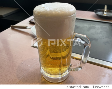 一杯生啤酒放在製作大阪燒的煎鍋桌前。 一杯生啤酒放在製作大阪燒的煎鍋桌前。 139524536