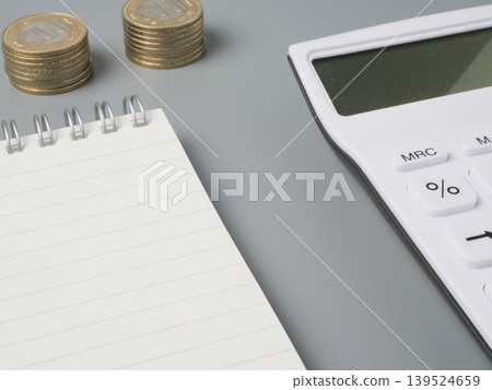 A money management image featuring a calculator, notebook, and loose change | Household budget management, income and expense calculation, and wealth building A money management image featuring a calculator, notebook, and loose change | Household budget management, income and expense calculation, and wealth building 139524659