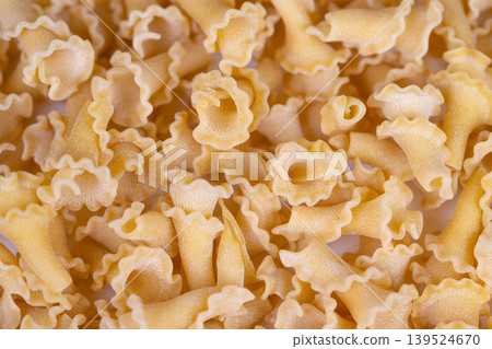 Rustic pasta with textured surface. Closeup view of artisanal pasta textures and colors. Fine details of rustic semolina pasta with golden hues and ruffled edges 139524670
