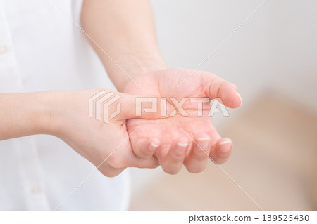 Woman with a pain in her hand Woman with a pain in her hand 139525430
