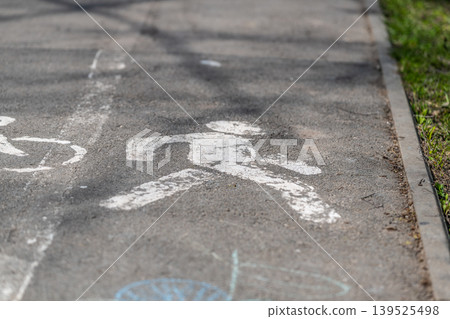 Pedestrian silhouette amidst soft park shadows. Inviting pedestrian lane featuring artistic chalk sketches and gentle tree shadows providing peaceful surroundings Pedestrian silhouette amidst soft park shadows. Inviting pedestrian lane featuring artistic chalk sketches and gentle tree shadows providing peaceful surroundings 139525498