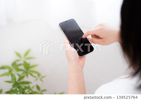 Hands of a woman operating a smartphone 139525764