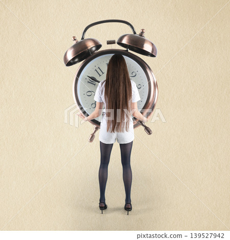 Woman hiding behind giant alarm clock deadline Woman hiding behind giant alarm clock deadline 139527942