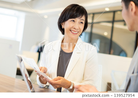一位年長的女性和一位年輕的商人正在會面。 一位年長的女性和一位年輕的商人正在會面。 139527954