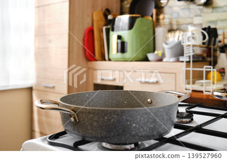 Cooking pot on the stove in a kitchen with wooden cabinets and various kitchen tools 139527960