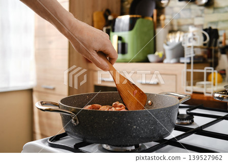 Stirring chopped chicken meat in frying pot with spatula 139527962