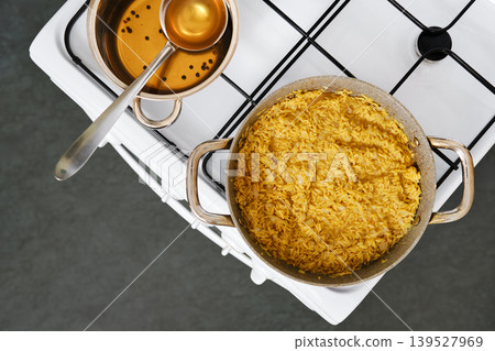 Cooking pasta orzo on the stove with a pot and a small bowl beside it 139527969