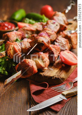 Delicious shish kebabs served on a wooden board with fresh vegetables and sauces 139527973