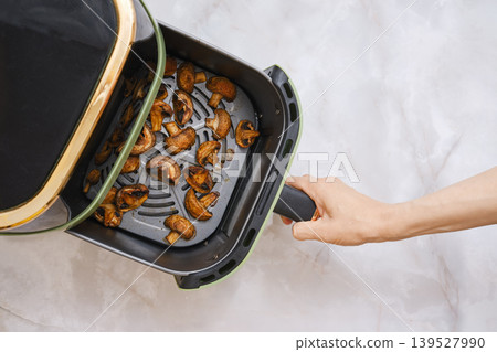 Cooking mushrooms in an air fryer on a kitchen counter during daytime 139527990