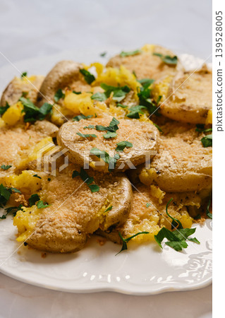 Crispy smashed potatoes served on a white plate with green herbs on top Crispy smashed potatoes served on a white plate with green herbs on top 139528005