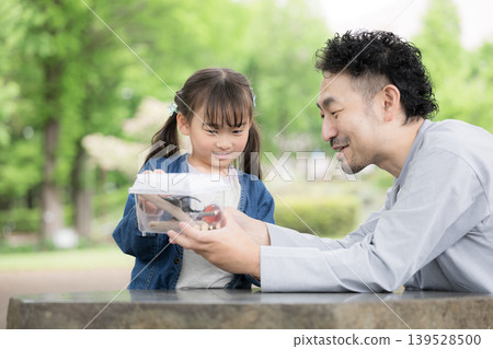 A portrait of a father and daughter observing insects, illustrating the educational aspects of nature experiences and learning about biology through insect collecting and other activities. A portrait of a father and daughter observing insects, illustrating the educational aspects of nature experiences and learning about biology through insect collecting and other activities. 139528500