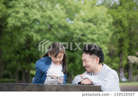 A portrait of a father and daughter observing insects, illustrating the educational aspects of nature experiences and learning about biology through insect collecting and other activities. A portrait of a father and daughter observing insects, illustrating the educational aspects of nature experiences and learning about biology through insect collecting and other activities. 139528507