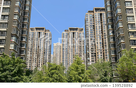 城市裡的高樓公寓大樓,綠樹環繞、藍天白雲的住宅區。 城市裡的高樓公寓大樓,綠樹環繞、藍天白雲的住宅區。 139528892