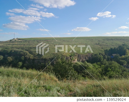 Fluffy white clouds over green landscape on a sunny day Fluffy white clouds over green landscape on a sunny day 139529024