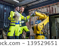 Black Male 20-30s and White Male 30-40s Engineers Reviewing Blueprints for Robotic Arm Automation 139529651