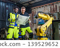 Black Male 20-30s and White Male 30-40s Engineers Reviewing Blueprints for Robotic Arm Automation 139529652