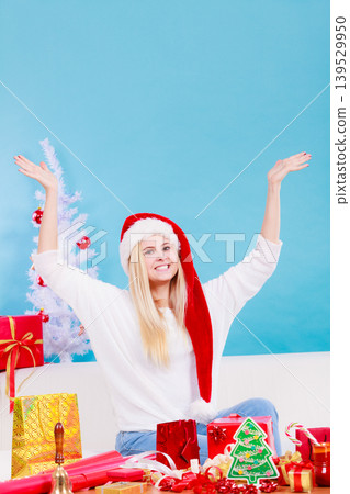 Woman in Santa hat preparing christmas gifts Woman in Santa hat preparing christmas gifts 139529950