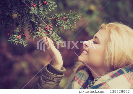 Woman dressed warmly looking at bush Woman dressed warmly looking at bush 139529962