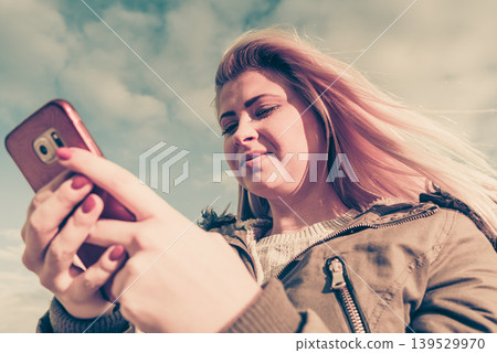 Woman using her smartphone outside, sunny day 139529970