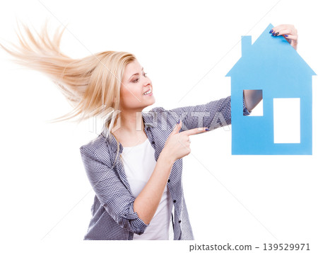 Woman holding blue paper house model cutout. Woman holding blue paper house model cutout. 139529971