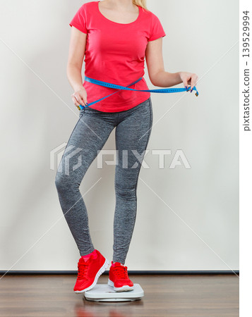 Woman wearing sportswear standing on weight machine Woman wearing sportswear standing on weight machine 139529994