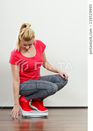 Woman wearing sportswear standing on weight machine Woman wearing sportswear standing on weight machine 139529995