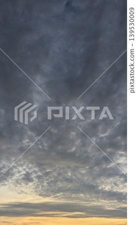 Dark storm clouds fill the morning sky, glowing with orange sunrise light at the horizon. This dramatic atmosphere captures natural weather transitions, moody dawn textures, scenic outdoor views. Dark storm clouds fill the morning sky, glowing with orange sunrise light at the horizon. This dramatic atmosphere captures natural weather transitions, moody dawn textures, scenic outdoor views. 139530009