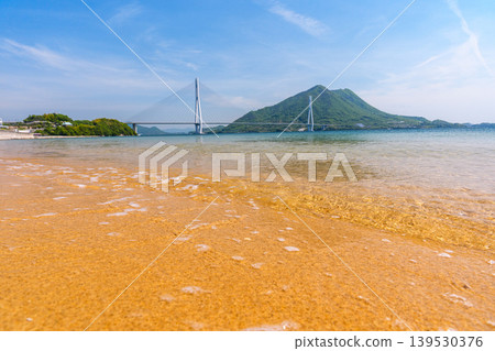 A stunning view of the Seto Inland Sea from the sandy beach of Omishima Island, overlooking the Tatara Bridge and Ikuchijima Island, along the Shimanami Kaido. 139530376