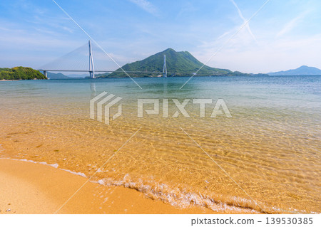 從大三島的沙灘上可以欣賞到瀨戶內海的壯麗景色,俯瞰著多多良橋和生口島,沿著島波海道而行。 從大三島的沙灘上可以欣賞到瀨戶內海的壯麗景色,俯瞰著多多良橋和生口島,沿著島波海道而行。 139530385
