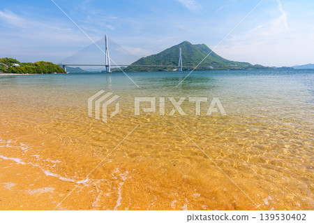 從大三島的沙灘上可以欣賞到瀨戶內海的壯麗景色,俯瞰著多多良橋和生口島,沿著島波海道而行。 從大三島的沙灘上可以欣賞到瀨戶內海的壯麗景色,俯瞰著多多良橋和生口島,沿著島波海道而行。 139530402