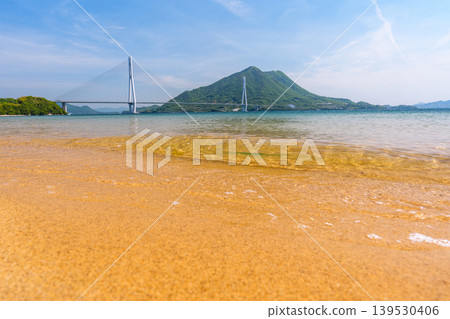 A stunning view of the Seto Inland Sea from the sandy beach of Omishima Island, overlooking the Tatara Bridge and Ikuchijima Island, along the Shimanami Kaido. A stunning view of the Seto Inland Sea from the sandy beach of Omishima Island, overlooking the Tatara Bridge and Ikuchijima Island, along the Shimanami Kaido. 139530406