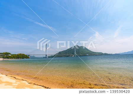 從大三島的沙灘上可以欣賞到瀨戶內海的壯麗景色,俯瞰著多多良橋和生口島,沿著島波海道而行。 從大三島的沙灘上可以欣賞到瀨戶內海的壯麗景色,俯瞰著多多良橋和生口島,沿著島波海道而行。 139530420