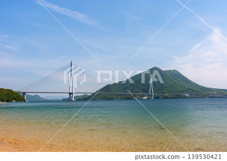 A stunning view of the Seto Inland Sea from the sandy beach of Omishima Island, overlooking the Tatara Bridge and Ikuchijima Island, along the Shimanami Kaido. 139530421