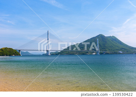 A stunning view of the Seto Inland Sea from the sandy beach of Omishima Island, overlooking the Tatara Bridge and Ikuchijima Island, along the Shimanami Kaido. A stunning view of the Seto Inland Sea from the sandy beach of Omishima Island, overlooking the Tatara Bridge and Ikuchijima Island, along the Shimanami Kaido. 139530422