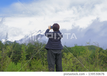 A female traveler photographs the spectacular scenery of the Northern Alps. 139530676