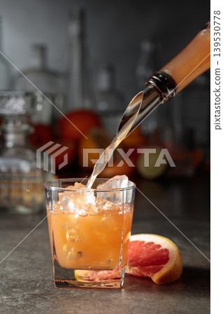 Grapefruit juice is poured into a glass with ice. Grapefruit juice is poured into a glass with ice. 139530778