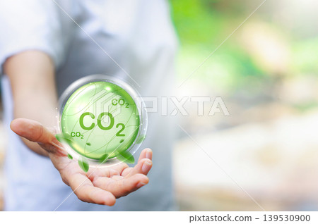 Hand holding glowing green CO2 bubble. Carbon dioxide reduction, net zero emissions, and climate change concept. Eco-friendly sustainable environmental protection and nature conservation background. 139530900