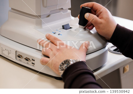 Hands adjusting focus knob on microscope stage for scientific observation with precision control in laboratory setting Hands adjusting focus knob on microscope stage for scientific observation with precision control in laboratory setting 139530942