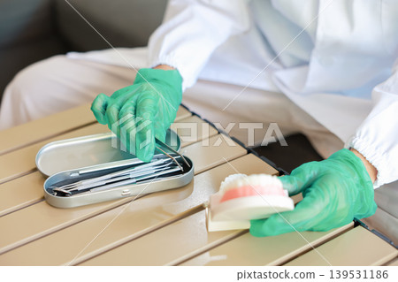 Macro close up shot of a sharp syringe needle tip with a clear liquid drop. Blurred doctor hand in a green latex glove holding medicine vaccine dose for injection. Healthcare and medical concept. 139531186