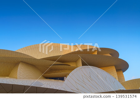Doha, Qatar - Jan 06 2024, a panoramic view of National Museum of Qatar facade, exterior, shaped like a desert rose, at evening with blue sky, Doha, Qatar Doha, Qatar - Jan 06 2024, a panoramic view of National Museum of Qatar facade, exterior, shaped like a desert rose, at evening with blue sky, Doha, Qatar 139531574