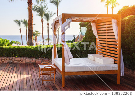A wide sun lounger with a large mattress near the pool, a place for luxurious relaxation 139532208