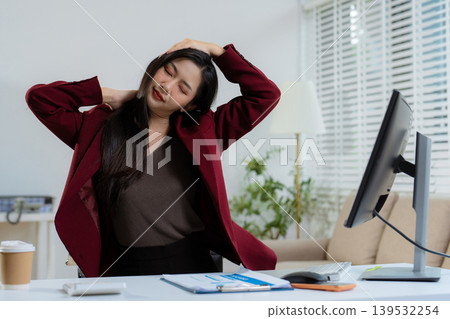 Businesswoman stretches to ease office syndrome from prolonged sitting. Businesswoman stretches to ease office syndrome from prolonged sitting. 139532254