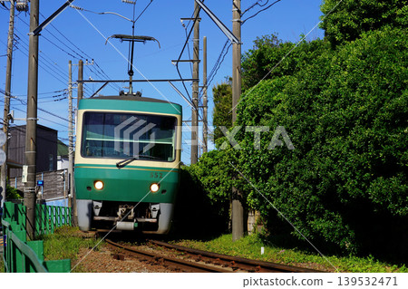 江之電500系列車駛過稻村崎住宅區的彎道。 江之電500系列車駛過稻村崎住宅區的彎道。 139532471