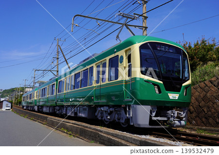 江之電700系列車在藍天白雲下沿著海邊筆直的道路行駛。 139532479