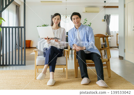 A young Japanese celebrity couple sits side-by-side in chairs in the living room, smiling. A young Japanese celebrity couple sits side-by-side in chairs in the living room, smiling. 139533042
