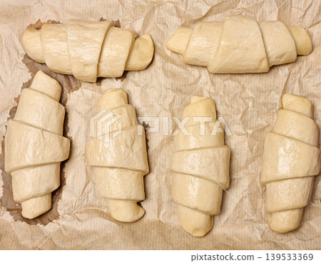 Uncooked croissant blanks on parchment paper Uncooked croissant blanks on parchment paper 139533369